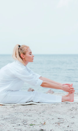 Mujer haciendo yoga en la playa