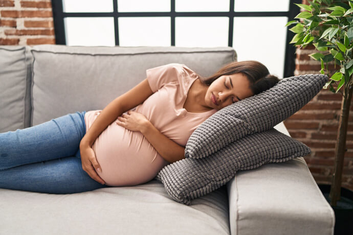 mujer joven embarazada durmiendo de lado en el sofá