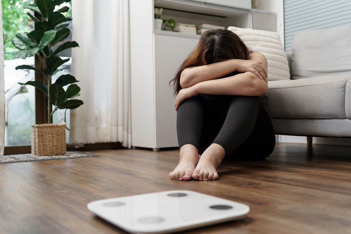 Una mujer con una báscula preocupándose por la pérdida de peso.