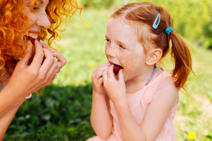 Mamá e hija comiendo frambuesas