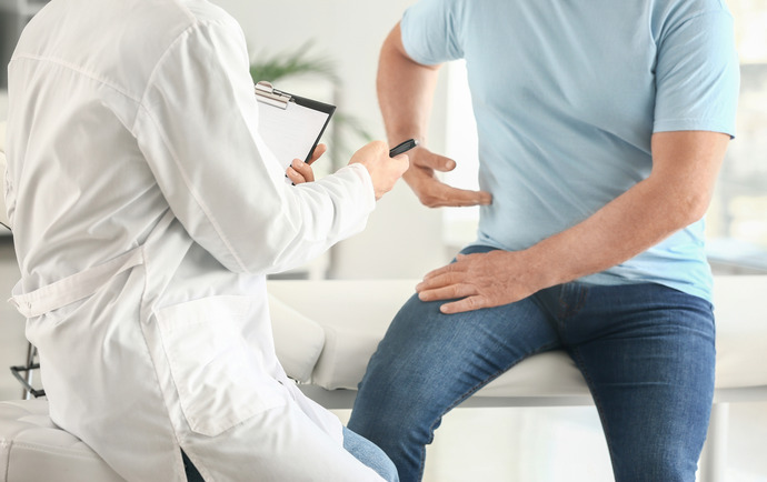 Hombre en la consulta médica señalando su zona abdominal