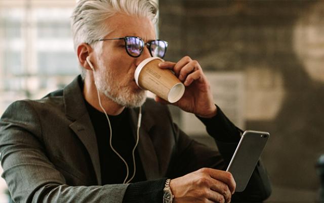 Hombre tomando café mientras observa su celular