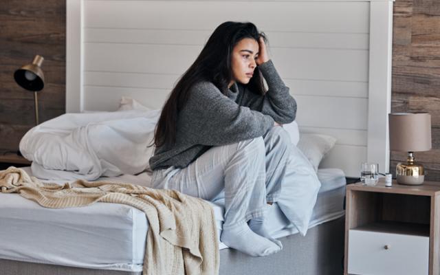 Mujer triste al lado de su cama