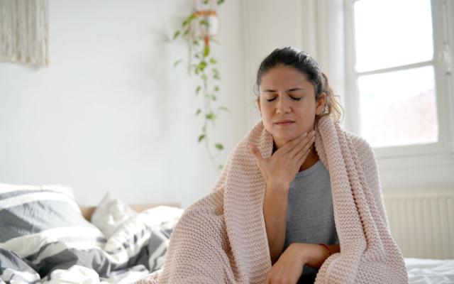 Mujer con manta sobre los hombros y dolor de garganta