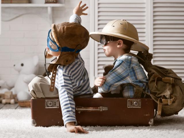 Niños jugando a viajar en avión dentro de una maleta