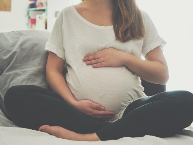 Embarazada sentada sujetándose la barriga