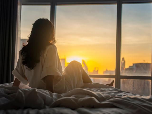 Mujer despertándose con la luz del sol desde su ventana