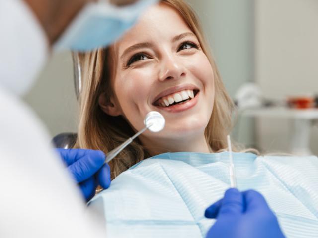 Dentista revisando si una mujer toma vitaminas para fortalecer sus dientes.