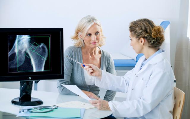 Médico explicando a paciente cómo prevenir la osteoporosis. 