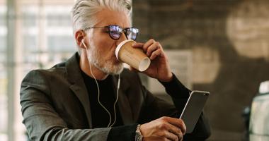 Hombre tomando café mientras observa su celular