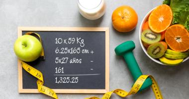 Elementos representativos de una vida saludable: manzana, cítricos, cinta métrica, pesa liviana