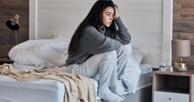 Mujer triste al lado de su cama